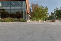 the entrance to a tall office building is shown with trees and shrubs lining the path