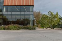 the entrance to a tall office building is shown with trees and shrubs lining the path