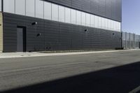 the bike is leaning against the building wall next to the street on which two people are riding