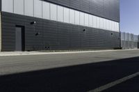 the bike is leaning against the building wall next to the street on which two people are riding