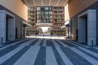 a person rides a bicycle in a large hallway way near tall buildings, the light reflects in the building's windows