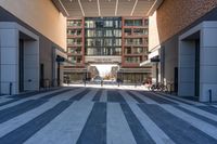 a person rides a bicycle in a large hallway way near tall buildings, the light reflects in the building's windows