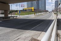 an empty highway with a parking lot underneath it and street lights and tall buildings on both sides