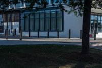 two people are standing on the sidewalk in front of an office building that has windows