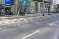 a road that has a building on the corner with a lot of windows in front