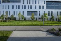 a city street surrounded by grass and tall buildings at the end of a street there is a paved pathway in front of the building