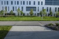 a city street surrounded by grass and tall buildings at the end of a street there is a paved pathway in front of the building