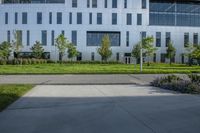 a city street surrounded by grass and tall buildings at the end of a street there is a paved pathway in front of the building