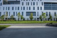 a city street surrounded by grass and tall buildings at the end of a street there is a paved pathway in front of the building