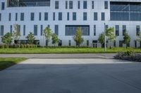 a city street surrounded by grass and tall buildings at the end of a street there is a paved pathway in front of the building