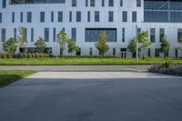 a city street surrounded by grass and tall buildings at the end of a street there is a paved pathway in front of the building