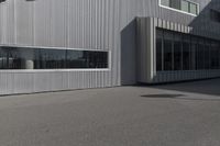 man doing a trick on a skateboard while standing in front of a building with two doors and windows