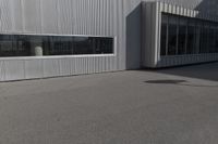 man doing a trick on a skateboard while standing in front of a building with two doors and windows