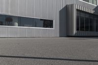 man doing a trick on a skateboard while standing in front of a building with two doors and windows