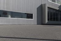 man doing a trick on a skateboard while standing in front of a building with two doors and windows