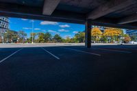 an empty parking lot surrounded by buildings and trees in the fall season with a blue sky above