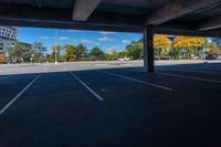 an empty parking lot surrounded by buildings and trees in the fall season with a blue sky above