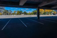 an empty parking lot surrounded by buildings and trees in the fall season with a blue sky above