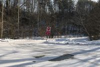 a sign that has a stop written next to it with snow on the ground nearby