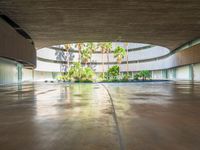 a large courtyard has concrete floors with trees and palm trees, a circular water feature and a low circular dome