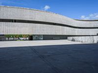 a concrete building with several large circular windows and multiple parked bikes parked outside of it