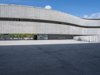 a concrete building with several large circular windows and multiple parked bikes parked outside of it