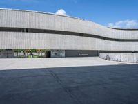 a concrete building with several large circular windows and multiple parked bikes parked outside of it