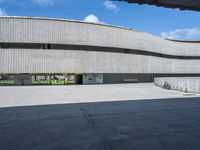 a concrete building with several large circular windows and multiple parked bikes parked outside of it