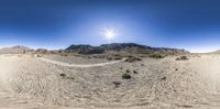 a 360 - view picture of mountains in a desert landscape with a sun shining over the top