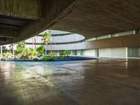 the concrete ground in front of an atrium building with a round roof on one side