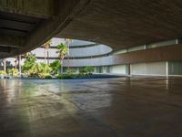 the concrete ground in front of an atrium building with a round roof on one side