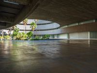 the concrete ground in front of an atrium building with a round roof on one side