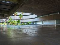 the concrete ground in front of an atrium building with a round roof on one side