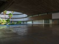 there is an empty concrete room with a pool and palm trees in the distance to the left