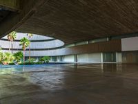 there is an empty concrete room with a pool and palm trees in the distance to the left