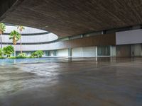 there is an empty concrete room with a pool and palm trees in the distance to the left