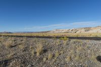 railroad tracks running through the middle of a desert landscape with mountains in the distance at the side