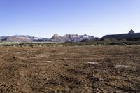 a barren field and mountain ranges, with a few snow patches in the dirt on the ground