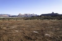 a barren field and mountain ranges, with a few snow patches in the dirt on the ground