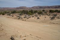 a road on a desert side with mountains in the back ground and dirt in front