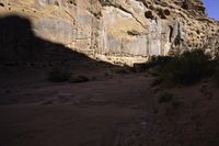 a person hiking up some steps near cliffs and scrubs, and has a backpack on his back