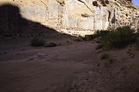 a person hiking up some steps near cliffs and scrubs, and has a backpack on his back