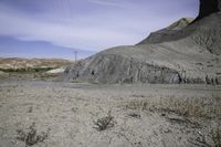 an abandoned mountain side with a dirt road near by and power lines above it in the distance