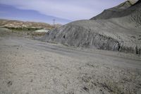 an abandoned mountain side with a dirt road near by and power lines above it in the distance