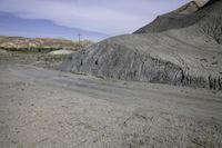 an abandoned mountain side with a dirt road near by and power lines above it in the distance