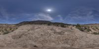 an image of a full moon setting over a desert hill and a tree lined field