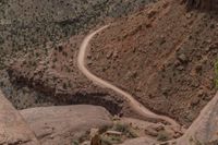 a vehicle traveling down a winding rocky road with sparse vegetation on either side of it