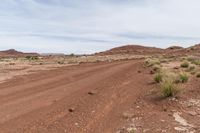 dirt road through desert with rock in the distance on sunny day outside of town in southwest colorado