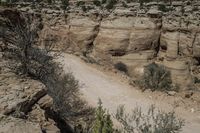 the dirt road is between two boulders in the mountains, with some scrub and shrub growing