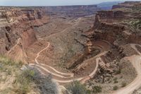 a view looking down from a high cliff into the desert with a two lane road on each side